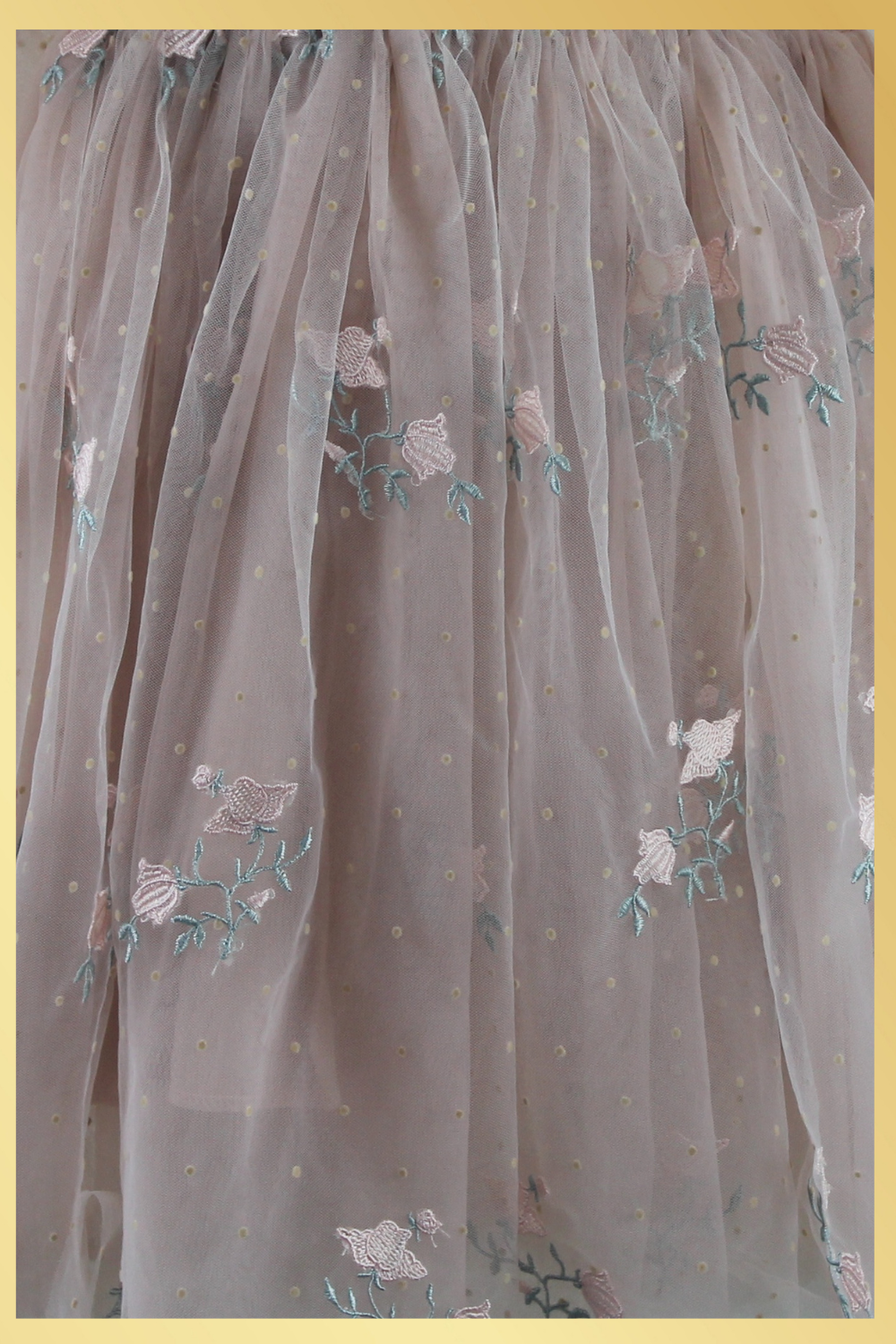 Close up of champagne tulle with swiss dot pater, and tulip embroidered flower and greenery.