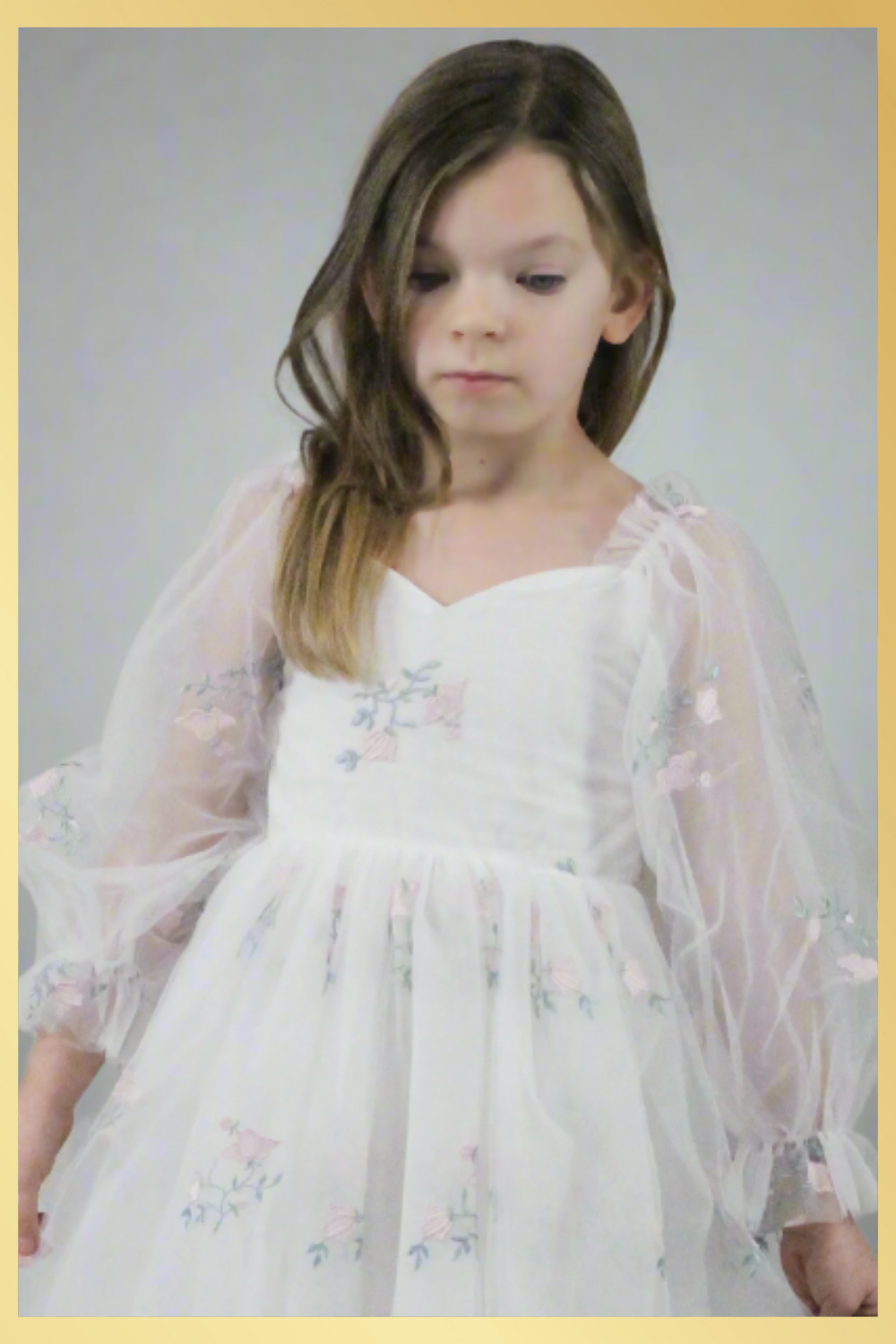 Close up of flower girl dress. White tulle with tulip print. Dress is long tulle sleeves and made to hit at the knee.