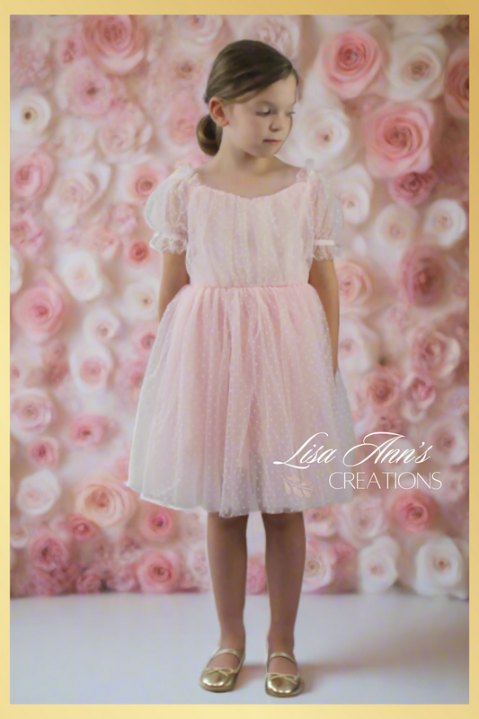 flower girl dress in a light pink swiss dot pattern. Puff short sleeves and knee length style. 